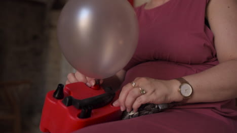 Kaukasische-Frau,-Die-Eine-Elektronische-Luftballonpumpe-Verwendet,-Die-Sich-Im-Inneren-Aufbläst