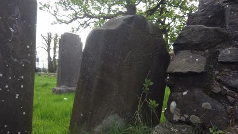 An-old-gravestone-leaning-on-an-old-wet-wall
