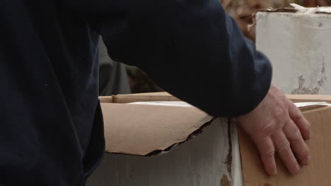 Man-opening-cardboard-box-with-block-of-ice-inside,-Slow-Motion