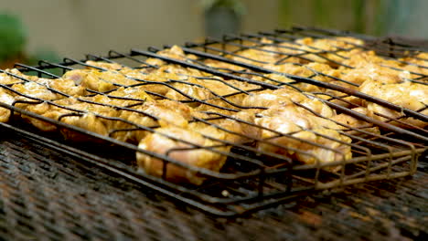 Barbecuing-chicken-on-open-fire,-turning-it-on-grid,-shallow-DOF
