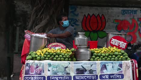 Seller-in-Fruit-juice-stall-on-road-side-in-India-selling-juice-wearing-mask-in-summer-season-during-covid-19-lockdown,-coronavirus-quarantine