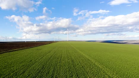 Wind-turbines-overlooking-the-green-farm-fields-on-a-sunny-day