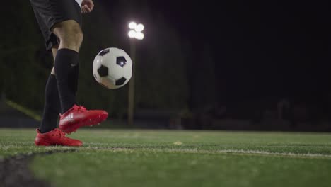 Die-Füße-Eines-Mannes-Mit-Roten-Stollen-Jonglieren-Mit-Einem-Fußball