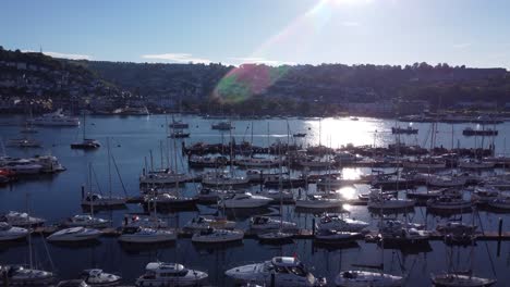 A-rising-shot-showing-many-pontoons-and-marinas-in-a-beautiful-harbour-whilst-the-evening-sun-is-just-starting-to-sit-behind-the-hills