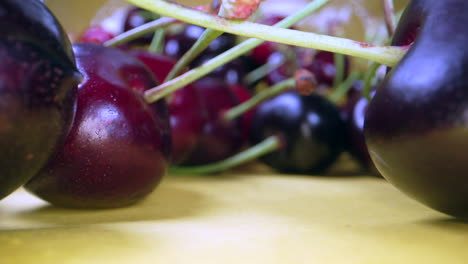 Macro-dolly-out-shot-of-ripe-red-cherries-on-table-during-sunny-day