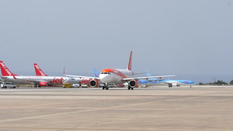 Aviones-De-Pasajeros-Rodando-En-El-Aeródromo-Del-Aeropuerto-De-Ibiza-En-Las-Islas-Baleares,-España-Con-Otros-Aviones-Estacionados-En-El-Fondo