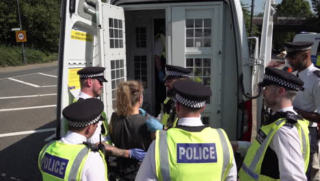 Police-put-a-surgical-mask-on-an-arrested-Stop-The-Arms-Fair-protestor-who-was-involved-in-a-road-blockade-before-putting-her-into-a-police-van