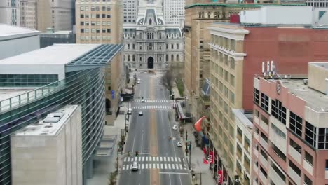 Aerial-view-overlooking-a-quiet-street-in-Philadelphia,-City-Hall-in-the-background---reverse,-drone-shot