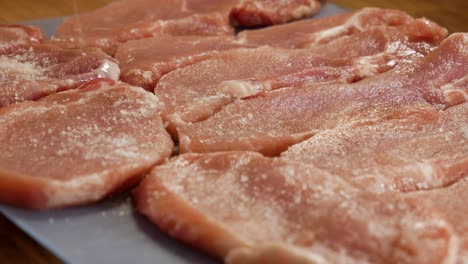 Gießen-Sie-Salz-Auf-Frische,-Rohe-Schweinefleischsteaks-In-Statischer-Nahansicht
