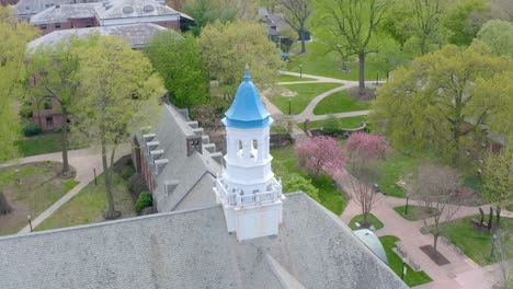 Aerial-of-blue-painted-bellfry-atop-large-building-on-American-university-campus-in-Lancaster-Pennsylvania,-USA