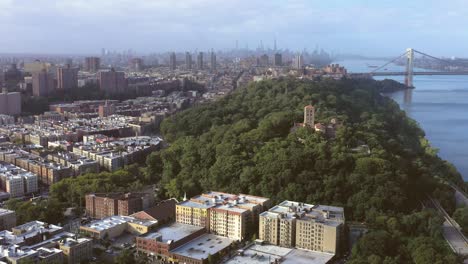 Gorgeous-aerial-flight-towards-The-Cloisters-museum-in-Upper-Manhattan-NYC-with-sweeping-views-of-uptown-neighborhoods,-Midtown,-and-the-George-Washington-Bridge-across-the-Hudson-River