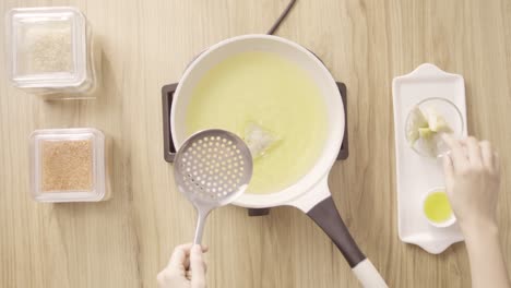 Cook-putting-food-in-boiling-oil-in-a-white-pot,-top-view-static