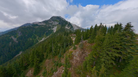 FPV-Drone-Shot-Of-Pine-Forest-On-Majestic-Mountain-Range-With-Clouds-In-Squamish,-BC,-Canada