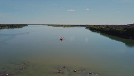 Wide-aerial-shot-following-a-small-ferry-sailing-on-the-Sao-Francisco-River-in-rural-Brazil