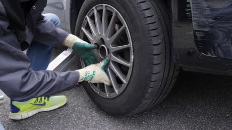 Do-it-yourself-man-changes-tires-on-his-car,-and-tighten-with-a-cross-wrench