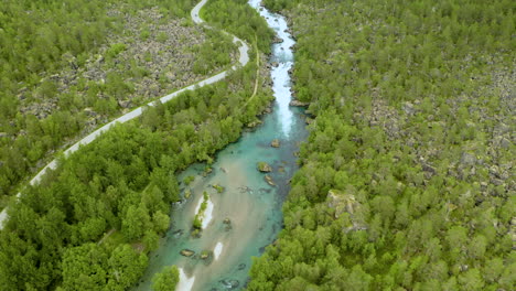 Luftaufnahme-Des-Flusses-Valldola-Mit-Schmaler,-Kurvenreicher-Straße-Und-Grünem-Wald-In-Norwegen