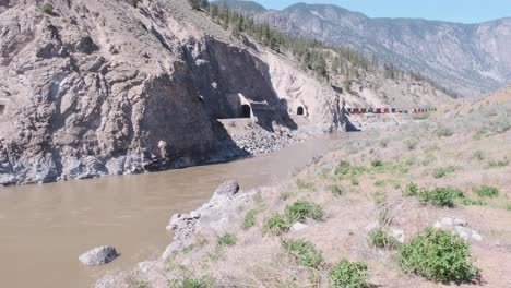 Canadian-Pacific-freight-train-passes-tunnels-in-river-canyon