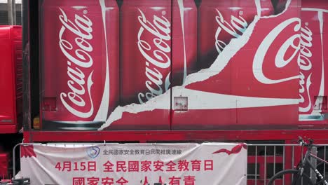 Fußgänger-Gehen-Am-Logo-Der-Amerikanischen-Erfrischungsgetränkemarke-Coca-Cola-Vorbei,-Das-Auf-Ihrem-Lieferwagen-In-Hongkong-Zu-Sehen-Ist