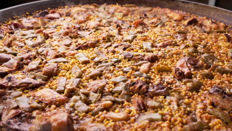 Paella-Valenciana-in-a-big-pan-made-with-rice,-chicken-and-vegetables-during-cooking