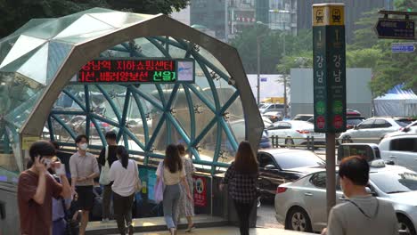 Ausgang-1-Des-Bahnhofs-Gangnam,-Menschen,-Die-Während-Der-Hauptverkehrszeit-In-Seoul-Bei-Sonnenuntergang-Am-Eingang-Des-Bahnhofs-Gangnam-Spazieren,-Südkorea,-Mit-Stadtverkehr-Im-Hintergrund