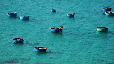 Empty-Vietnamese-fishing-coracle-basket-boats-moored-and-floating-in-turquoise-Asian-sea