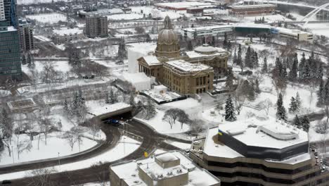 Aerial-hold-during-the-first-major-snow-fall-in-downtown-Edmonton-whereby-the-British-and-Canadian-flag-at-Alberta-Legislature-are-half-mass-honouring-Prince-Philip-of-Edinburgh-who-died-at-age-99-UK
