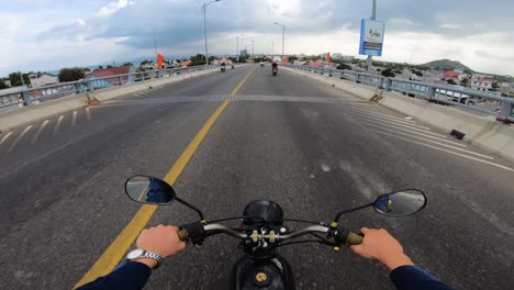 First-person-view-of-motorcyclist-riding-motorcycle-on-phan-rang-bridge,-Vietnam
