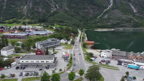 Summer-traffic-heading-for-rv7-Hardangervidda-mountain-in-Eidfjord---Aerial-over-road-looking-at-mountainside-and-seafront---Norway