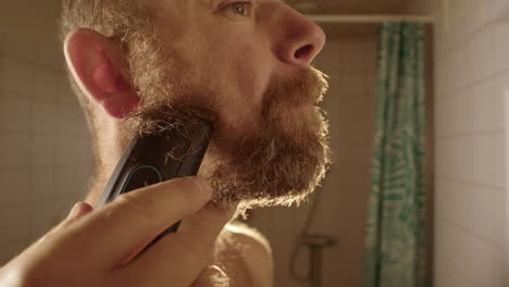 SLOW-MOTION,-a-bearded-man-starts-shaving-off-his-long-beard-in-a-bathroom