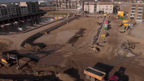 Aerial-reveal-showing-a-construction-site-of-new-luxury-apartment-building-project-in-Noorderhaven-neighbourhood-in-Hanseatic-city-Zutphen,-The-Netherlands,-between-recreational-port-and-train-tracks