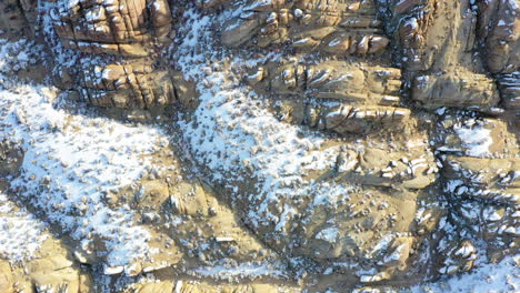 Rocky-landscape-covered-in-pure-white-snow,-aerial-top-down-view