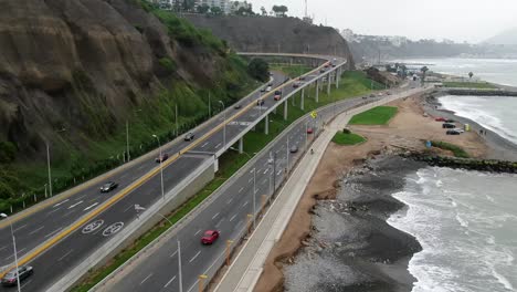 Luftaufnahme-Von-Autos,-Die-Auf-Einer-Malerischen-Fahrt-Am-Strand-Entlang-In-Lima,-Peru-Fahren