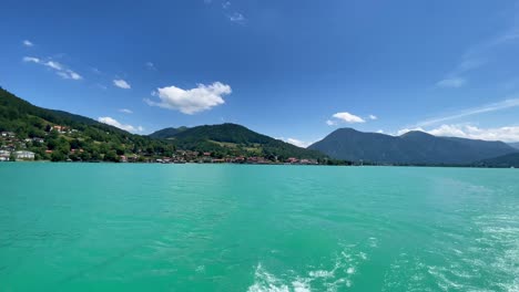 The-popular-bavarian-Tegernsee,-having-a-trip-over-the-turqouise-water-at-summertime,-filmed-from-a-ship-looking-backward-to-the-impressive-water-color-with-the-alps-in-the-background