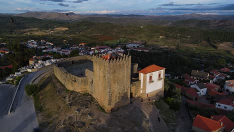 A-drone-captures-a-flock-of-birds-flying-past-the-Belmonte-Castle-tower-as-the-sunsets