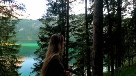 White-girl-with-blonde-hair,-wearing-a-green-top-and-sunglasses,-walks-next-to-the-famous-lake-Eibsee-in-Germany
