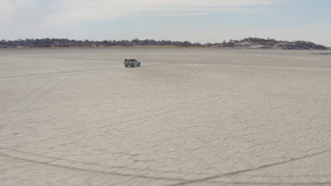 4x4-Car-Driving-On-Dry-Salt-Pan-Of-Makgadikgadi-Towards-Kubu-Island-In-Botswana,-South-Africa