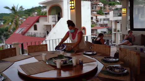 Hotel-or-resort-staff-setting-the-table-for-a-meal---revolving-or-orbiting-view-with-the-city-in-the-background