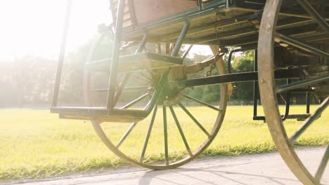 The-wheel-of-a-historic-carriage-rotates-on-a-sandy-path-with-the-sunrise-in-the-background