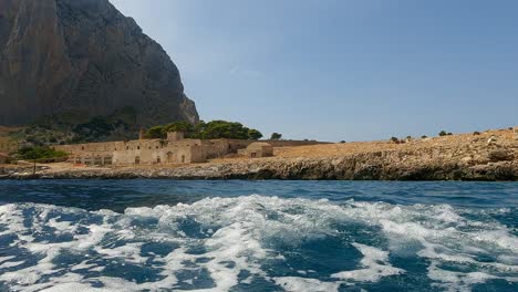 Old-Sicilian-seafront-Tonnara-Del-Secco-used-for-tuna-fishing-as-seen-from-boat-in-Sicily