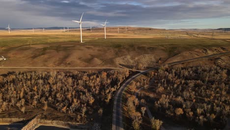 Cinematic-aerial-footage-of-wind-turbines-in-Canada-during-a-sunrise-that-illuminates-the-Rocky-mountains-in-the-background
