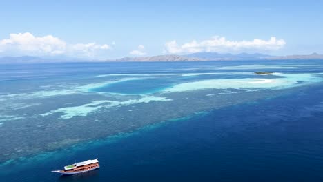 Paluau-Katangan-sandbank-reef-atoll-near-Komodo-Island-Indonesia-with-diving-boat-below,-Aerial-dolly-out-reveal-shot