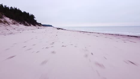 Beautiful-aerial-view-of-the-Baltic-sea-coastline,-overcast-day,-white-sand-beach-affected-by-sea-coastal-erosion,-calm-seashore,-wide-low-angle-drone-shot-moving-forward-fast