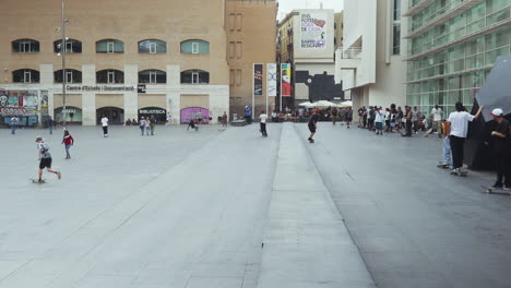 Barcelona---Plaça-dels-Àngels,-outside-the-Museum-of-Contemporary-Art-with-skateboarders-doing-tricks-and-a-crowd-watching