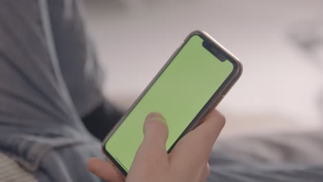 Ein-Junger-Mann-Scrollt-Entspannt-Durch-Sein-Handy-Mit-Grünem-Displaybild