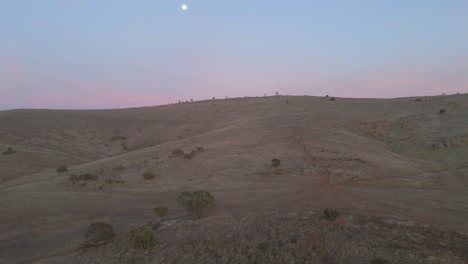 Aerial-flying-towards-Appila-Springs-hills-revealing-Endless-countryside-landscape,-Sunset-with-moon