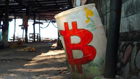 Full-focus-shot,-a-white-drum-with-a-red-bitcoin-logo-on-the-side-of-the-hut-on-the-bitcoin-beach-in-El-Salvador,-Mexico,-a-dog-sleeping-in-the-middle-of-the-hut