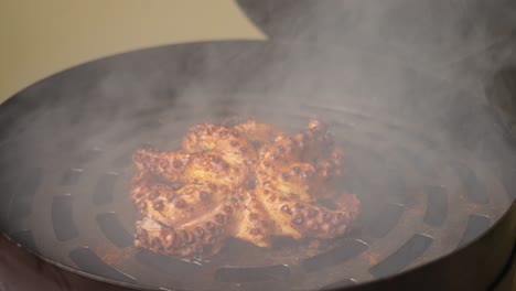 Cooking-delicious-chewy-octopus-with-spices-and-herbs-in-burning-charcoals-fire-on-bbq-grid-smoker,-perfectly-cooked-and-seared-in-golden-brown-with-aromatic-smoke-in-slow-motion