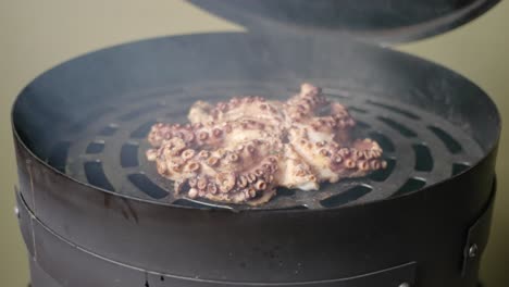 A-male-hand-open-up-the-lid-of-a-smoker-with-fresh-octopus-on-the-grill,-smoking-with-low-heat,-cinematic-slow-motion-shot