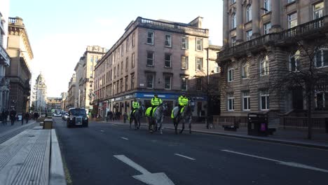 A-wide-shot-of-a-group-of-police-officers-and-their-horses-coming-down-a-city-road