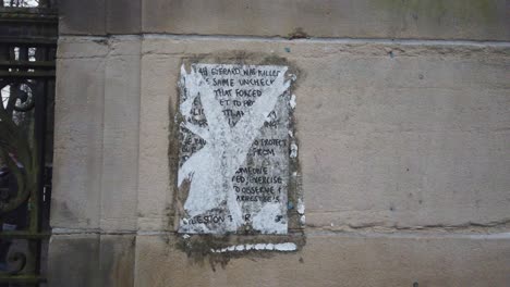 A-ripped-and-old-tribute-to-Sarah-Everard-on-the-main-entrance-wall-at-Queens-Park